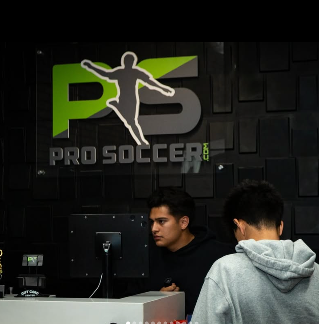 Two people in front of a Pro Soccer logo on a dark wall.