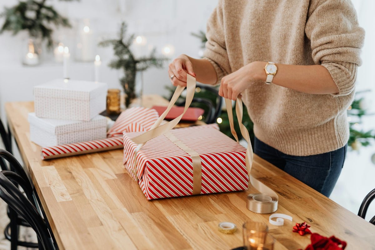 Holiday gift ideas - woman wrapping a gift on a table