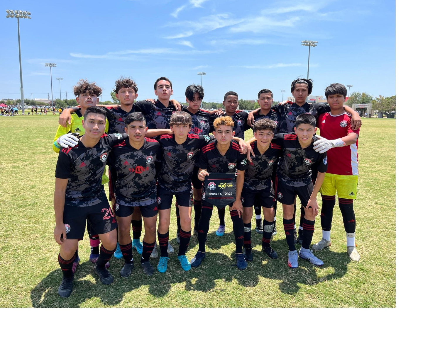 LAUFA soccer club team photo outdoors on soccer field during day. Team wearing black and red LAUFA jerseys 14 players in the image